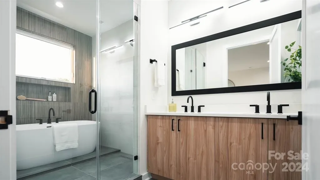 Modern bathroom with a tub, glass shower, and wooden vanity.