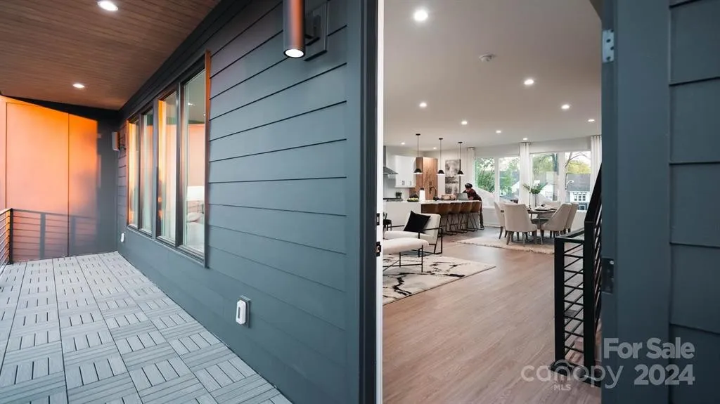 Exterior view of a modern home's entrance, featuring dark blue siding and a glimpse into the bright interior.
