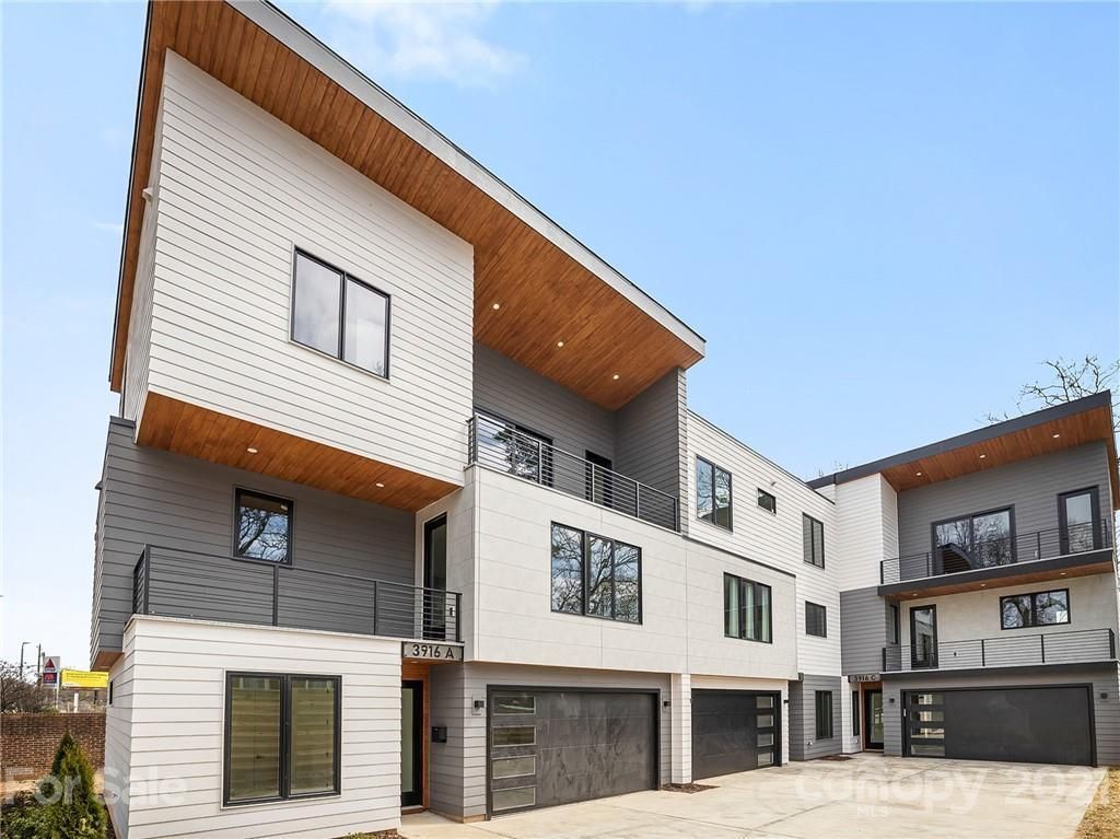 Modern townhouses with white siding, wood accents, and black garage doors.