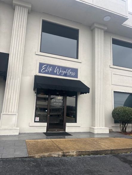 Exterior of Elite Weight Loss clinic, white building with dark awning and windows.