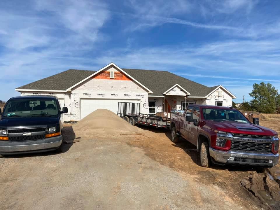 House under construction with vehicles parked in front.