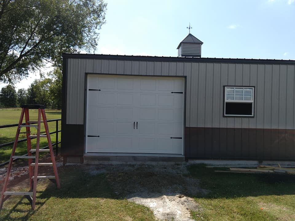 Garage with a white door, brown trim, and a small window under a blue sky.