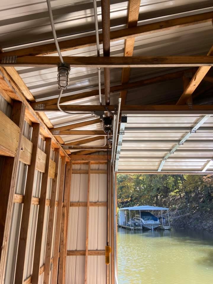 Wooden boat dock with a metal roof and a boat visible in the water.