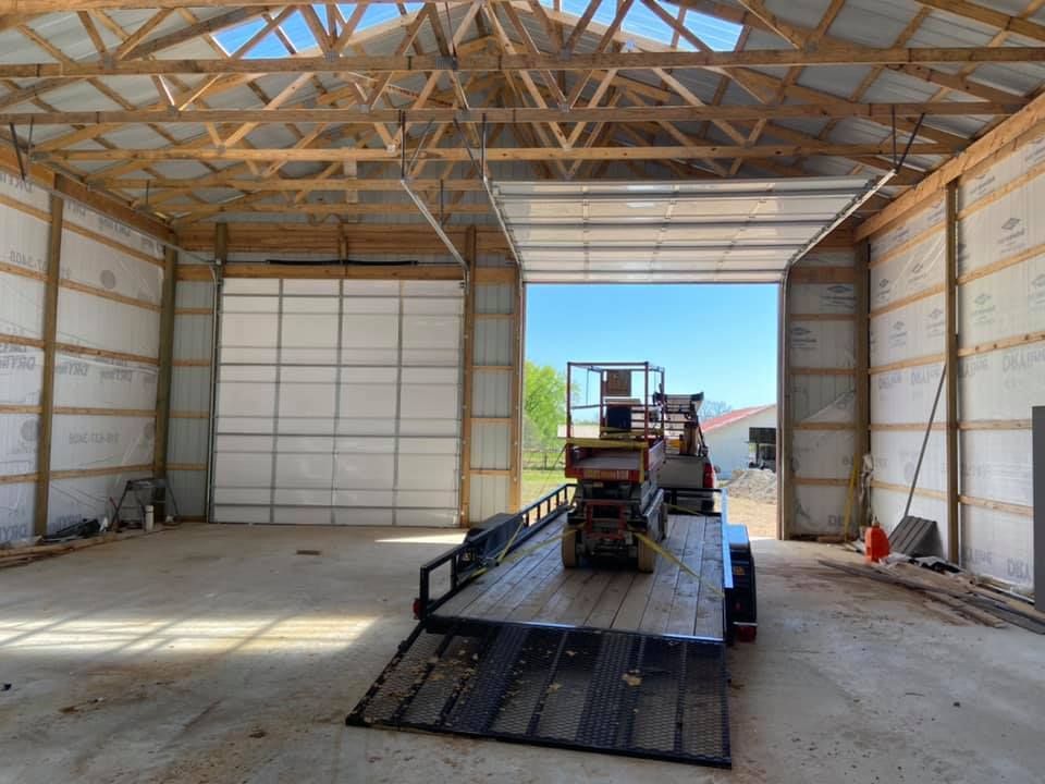 Interior of a new building with open garage doors; trailer with lift inside.