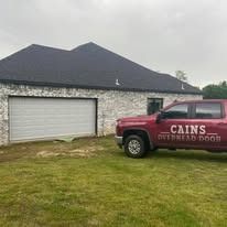 White brick building with a garage and a truck parked outside; CAINS OVERHEAD DOOR.