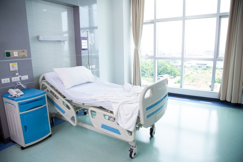 An Empty Hospital Room With a Bed, Nightstand, and Window — Brisbane Upper GI Surgery in Chermside, QLD