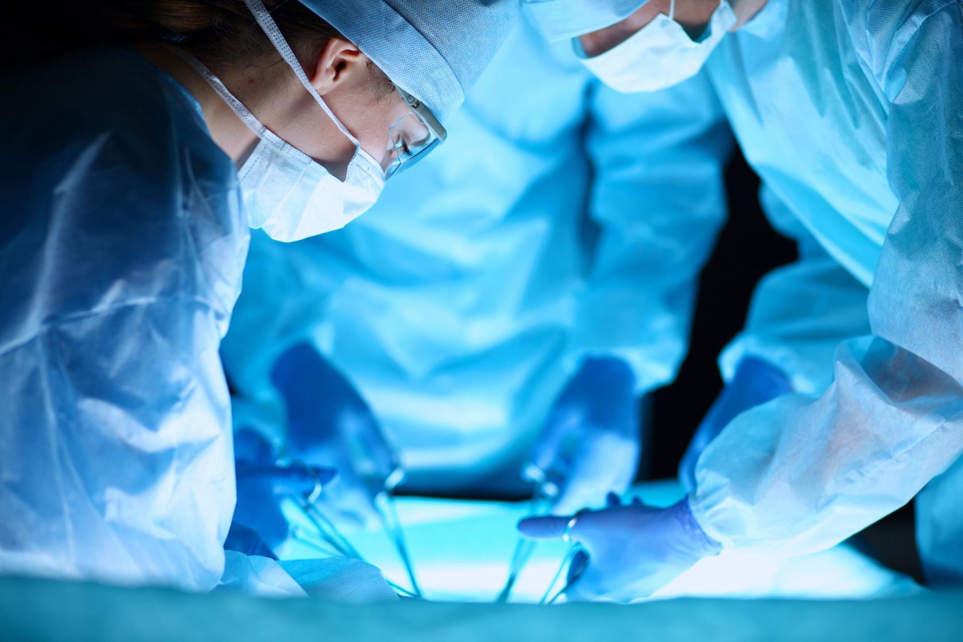 Surgeons In Blue Scrubs And Masks Perform Surgery Under Bright Lights — Brisbane Upper GI Surgery in Chermside, QLD