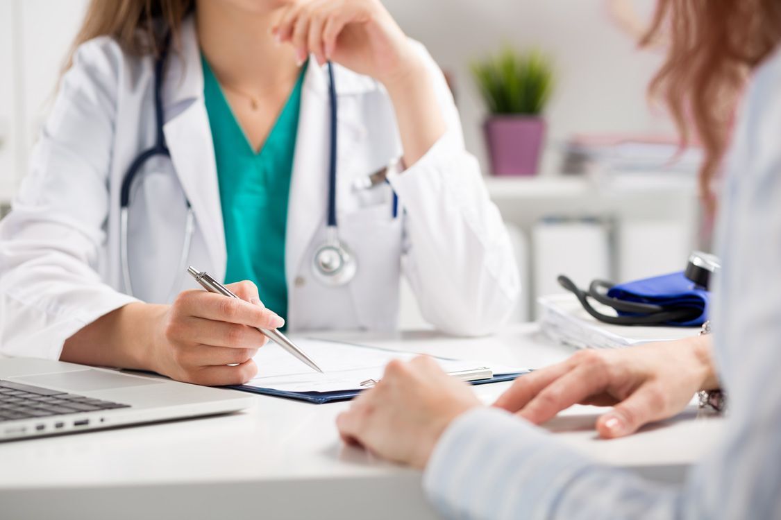A Doctor is Sitting at a Desk Talking to a Patient — Brisbane Upper GI Surgery in Chermside, QLD