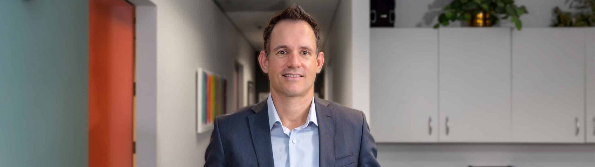 A Man in a Suit and Blue Shirt is Standing in a Hallway — Brisbane Upper GI Surgery in Chermside, QLD