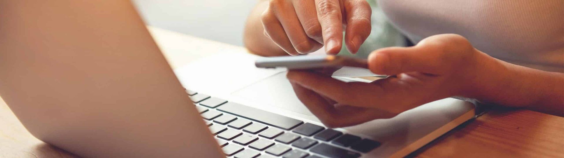 A Person is Using a Cell Phone in Front of a Laptop Computer — Brisbane Upper GI Surgery in Gold Coast, QLD