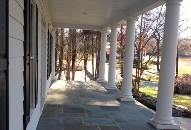 A porch with columns and a view of trees