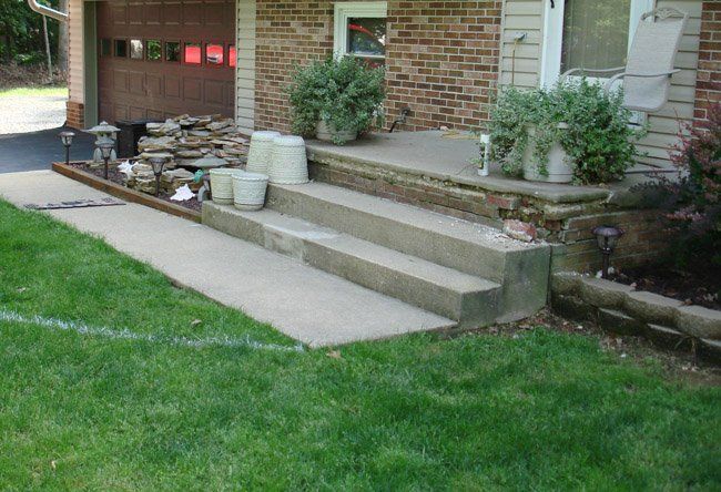 A brick house with a concrete porch and steps