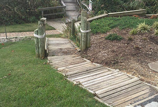 A wooden walkway leading to a staircase in a yard.