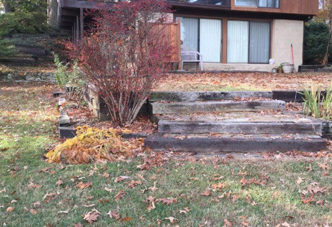 A house with seps leading up to it and leaves on the ground in front of it.