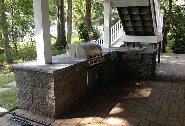 An outdoor kitchen with a grill and stairs in the background