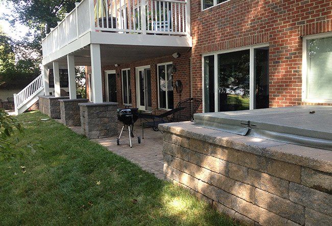 A brick house with a large deck and a hot tub in the backyard.