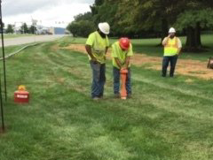 A group of construction workers are standing in a grassy field.