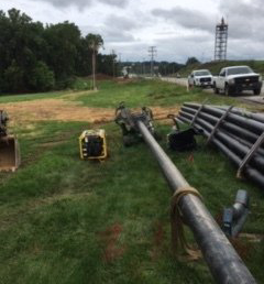 A bunch of pipes are laying on the grass in a field.