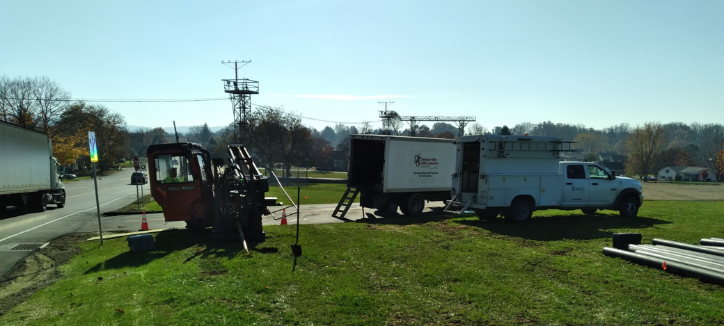 A white truck is parked in a grassy field next to a trailer.