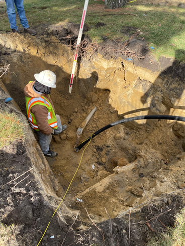 A construction worker is digging a hole in the ground.