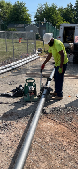 A man in a hard hat is working on a pipe.