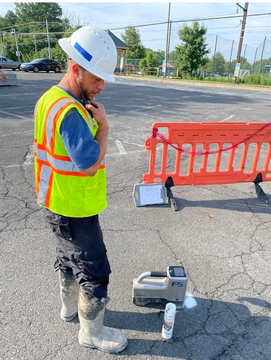 A man wearing a hard hat and safety vest is talking on a walkie talkie