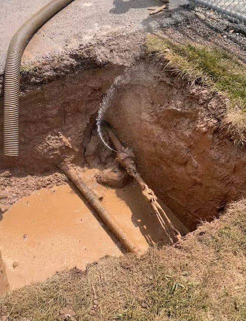 A hole in the ground with a hose coming out of it.
