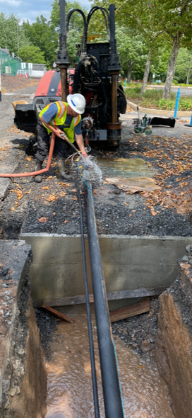 A man is working on a pipe in a hole in the ground.