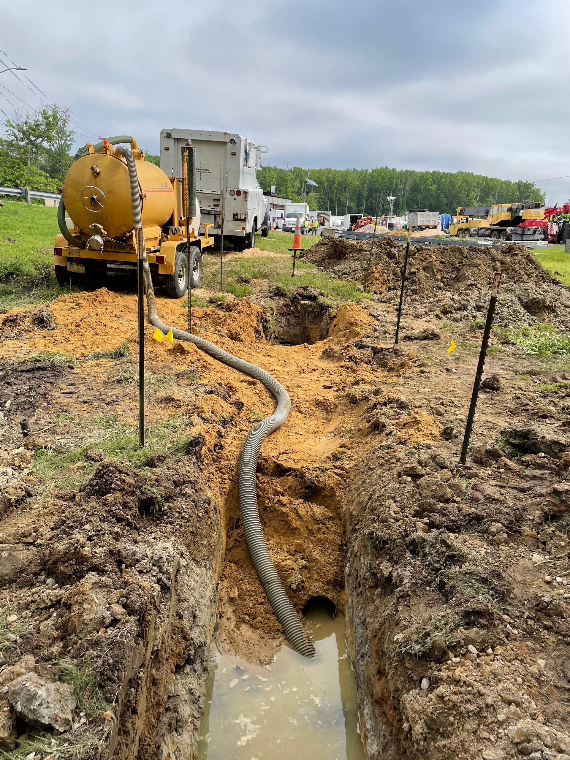 A vacuum truck is pumping water into a muddy trench.