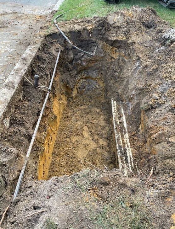 A large hole in the ground next to a sidewalk for a new force main.