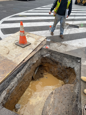 A man is standing next to a hole in the ground.