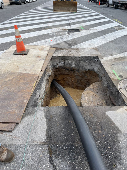 A black pipe is coming out of a hole in the ground.