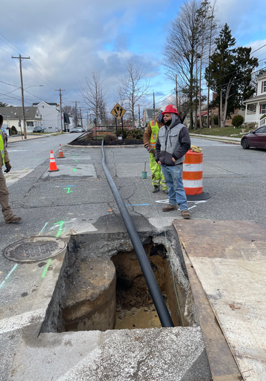 A group of construction workers are working on a pipe in a hole in the ground.