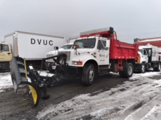 A dump truck with a snow plow attached to it