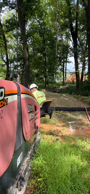 A man is sitting on the back of a machine in the woods.