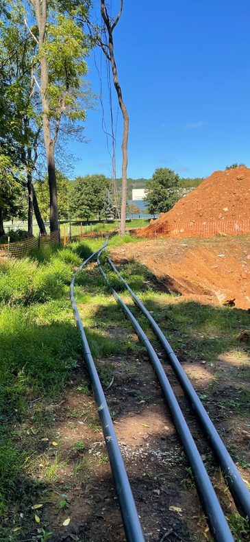 A bunch of pipes going through a field with trees in the background.