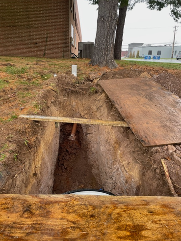 A person is digging a hole in the ground next to a building.