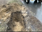 A car is driving down a road next to a pile of dirt.