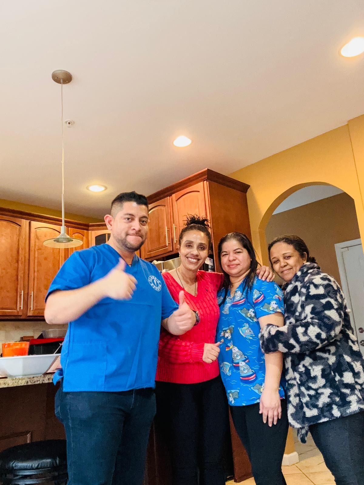 Four people standing together in a kitchen, smiling and posing for a photo.