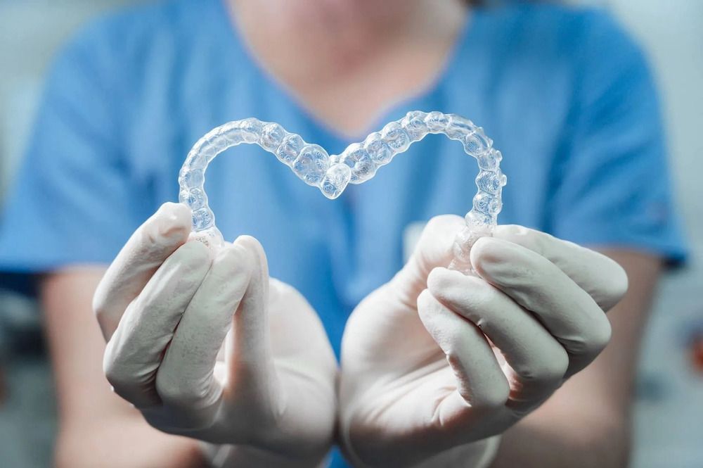 Dental professional holding clear aligners in shape of heart. 