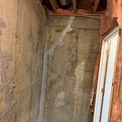 Basement wall with a crack sealed with tape, pink insulation peeking through. A door frame is visible on the right.
