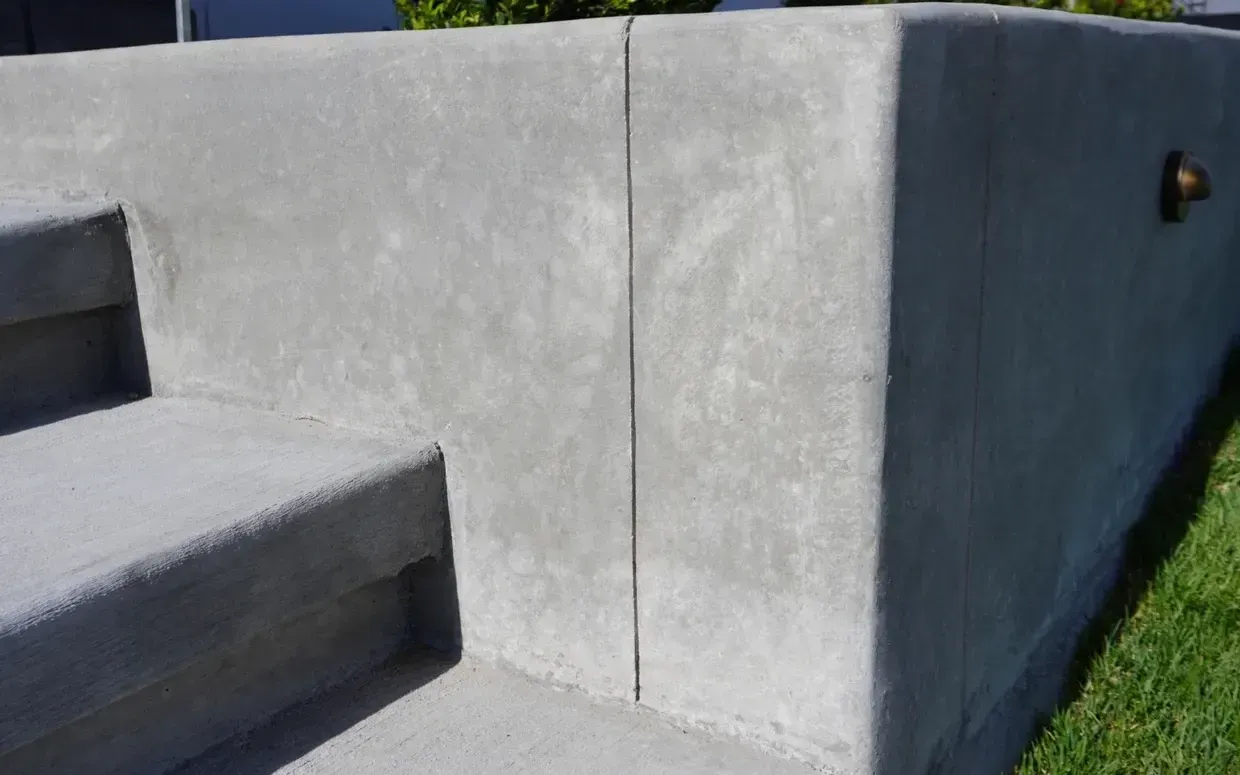 Concrete steps and retaining wall, gray with a vertical joint.