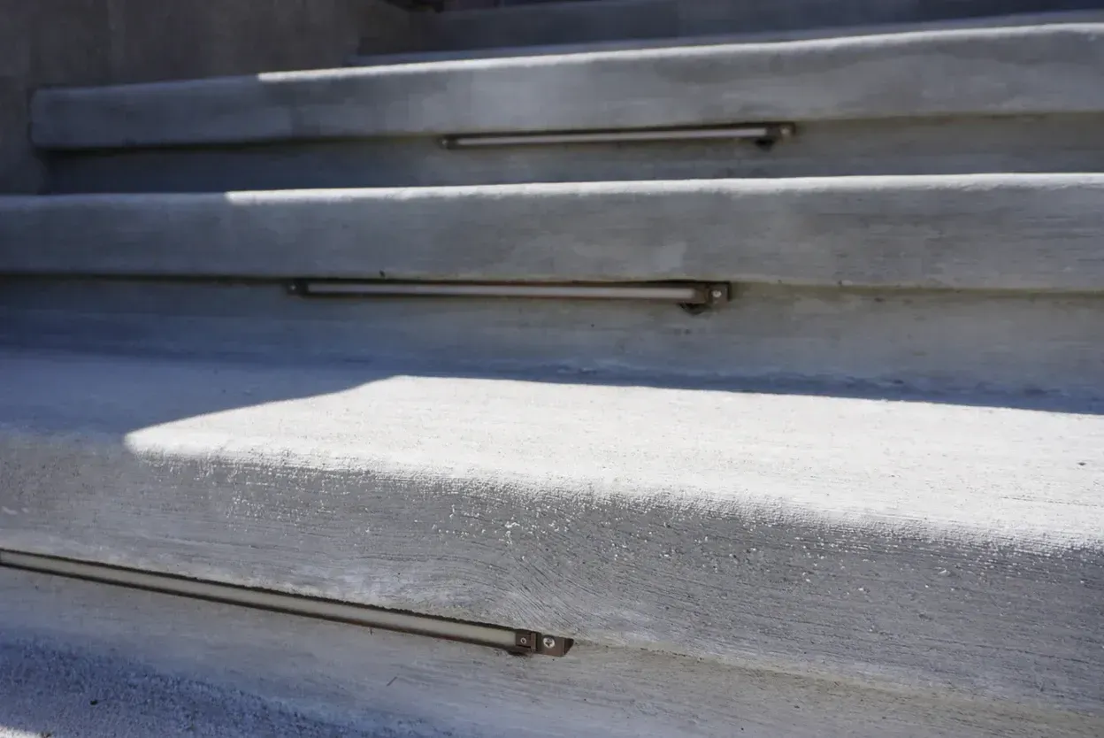Concrete outdoor steps with metallic handrails for each step.