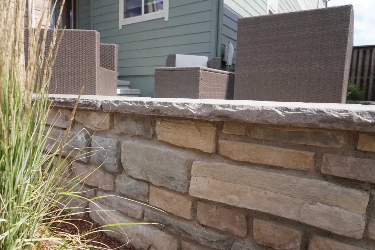 Stone retaining wall with patio furniture on a porch.