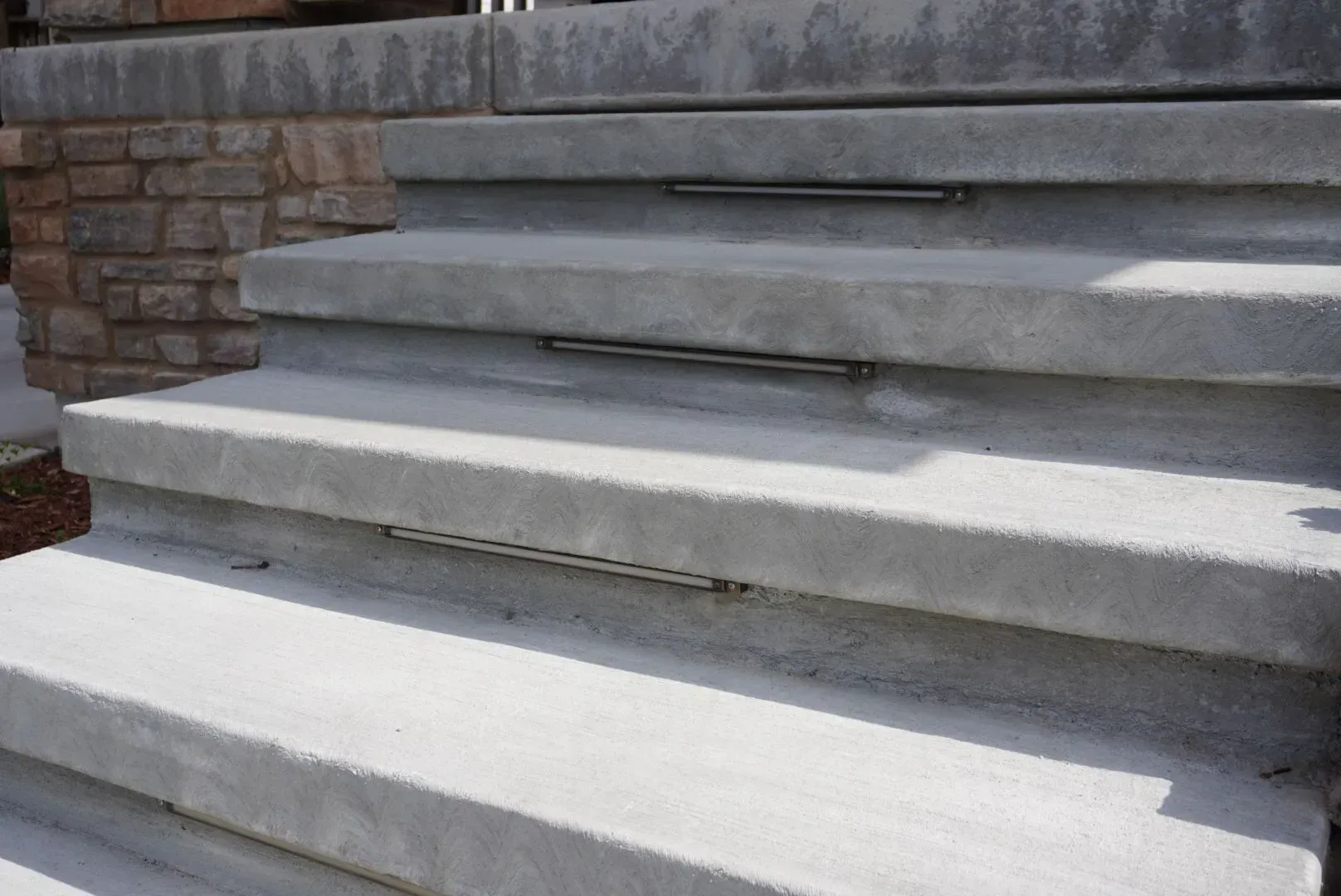 Concrete outdoor steps with metal strips built into each step for visual aid.