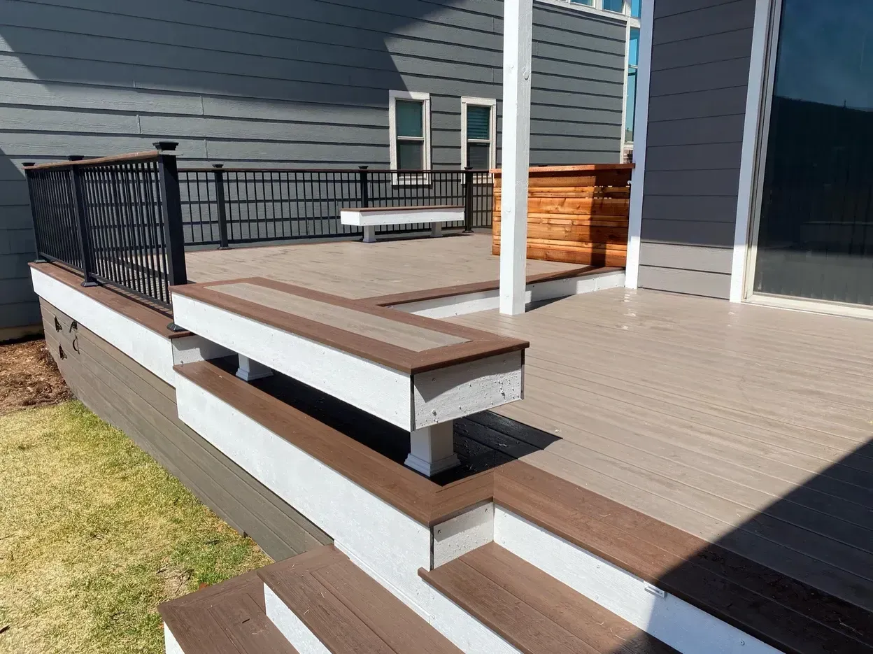 Composite deck with steps and seating, against a gray house.