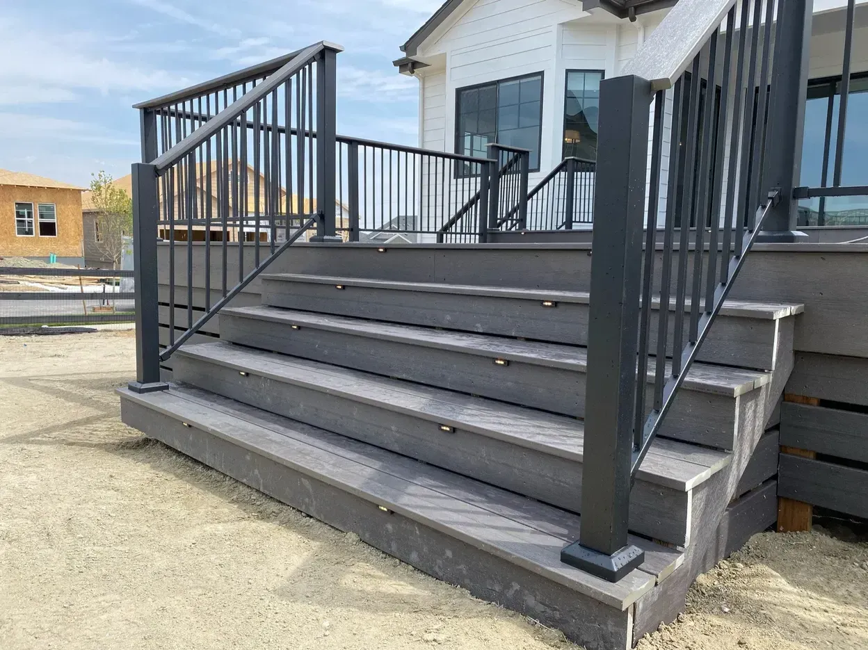 Gray composite deck and stairs with black metal railings. LED lights are on the steps.