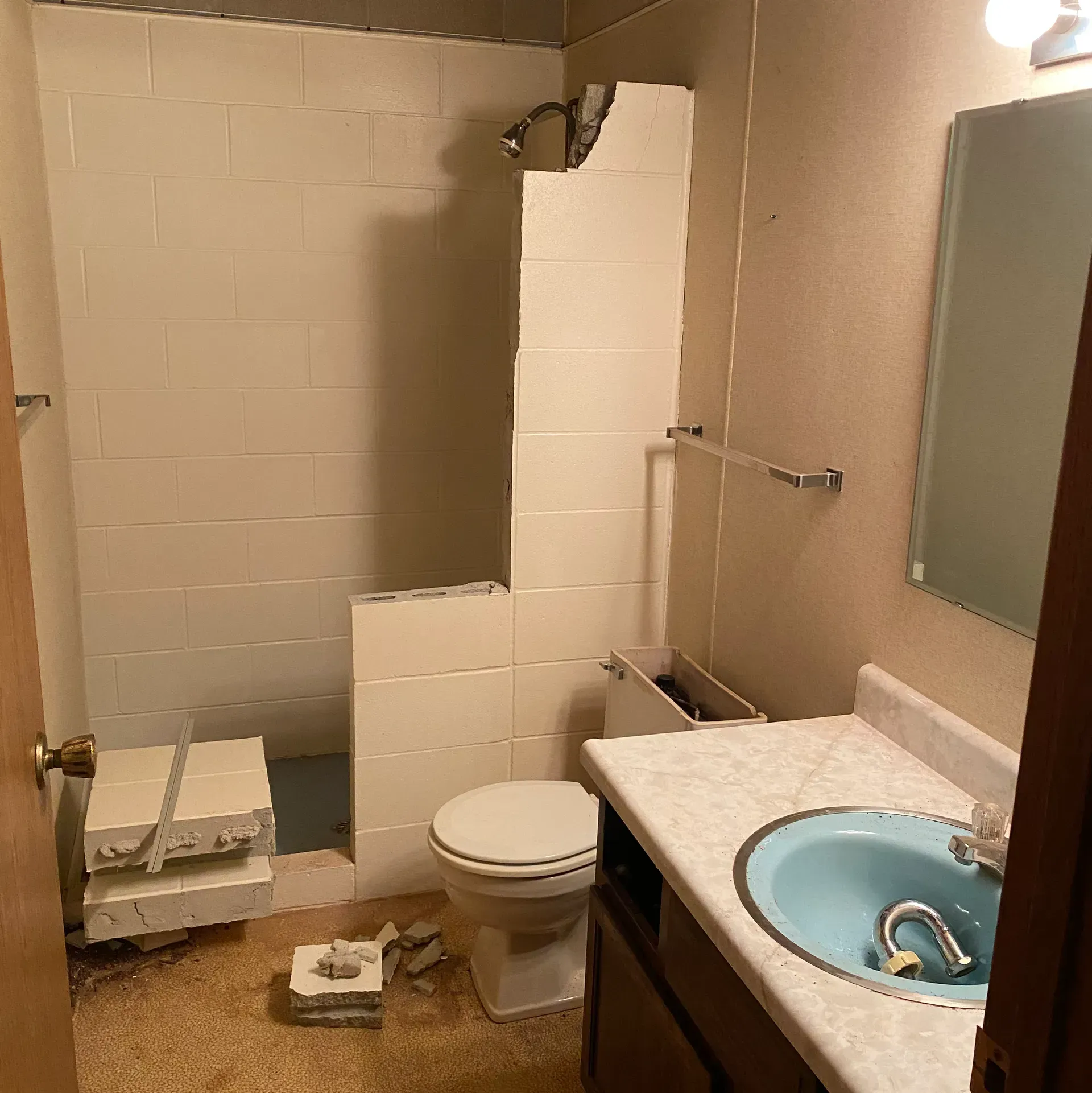 Bathroom with unfinished shower, toilet, blue sink, and brown cabinets.