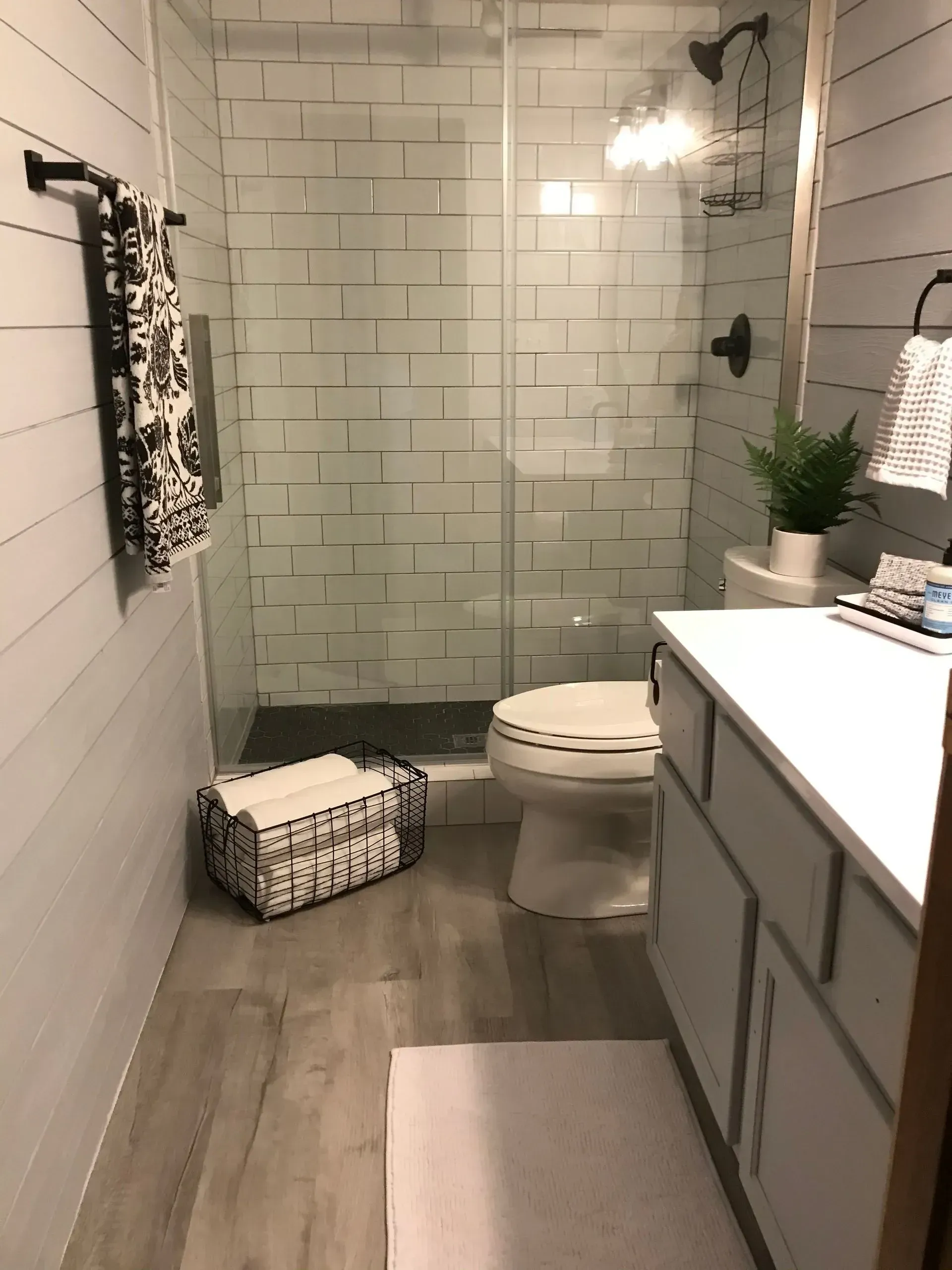 Modern bathroom with white walls, shower, toilet, sink, and gray flooring.