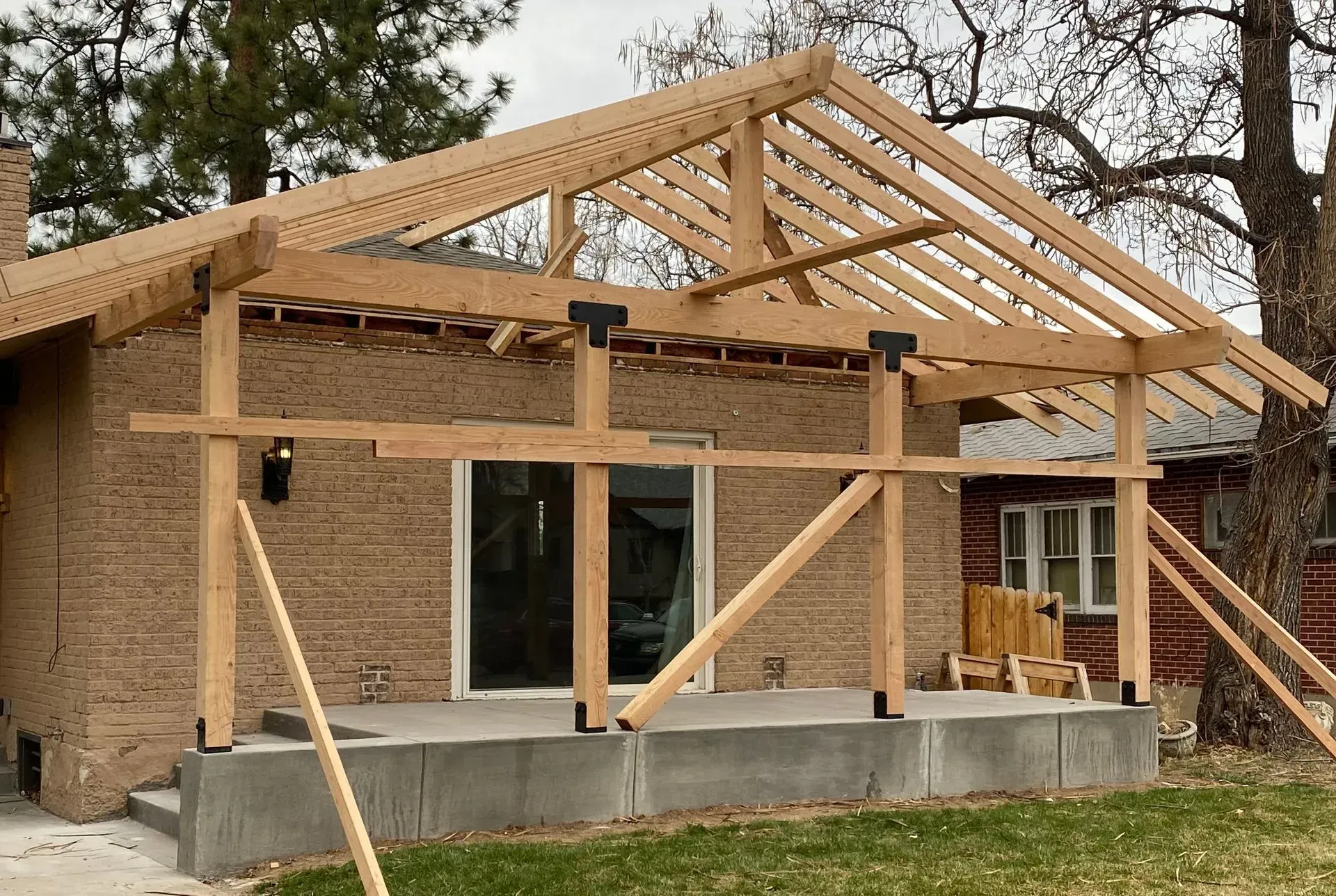 Construction of a wooden porch roof addition to a brick house.